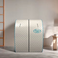 A quilted dome-shaped relaxation sauna tent with a diamond pattern, light gray exterior, and turquoise blue trim. The brand name 'Relax' is printed in a turquoise oval logo on the front.