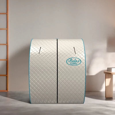 A quilted dome-shaped relaxation sauna tent with a diamond pattern, light gray exterior, and turquoise blue trim. The brand name 'Relax' is printed in a turquoise oval logo on the front.